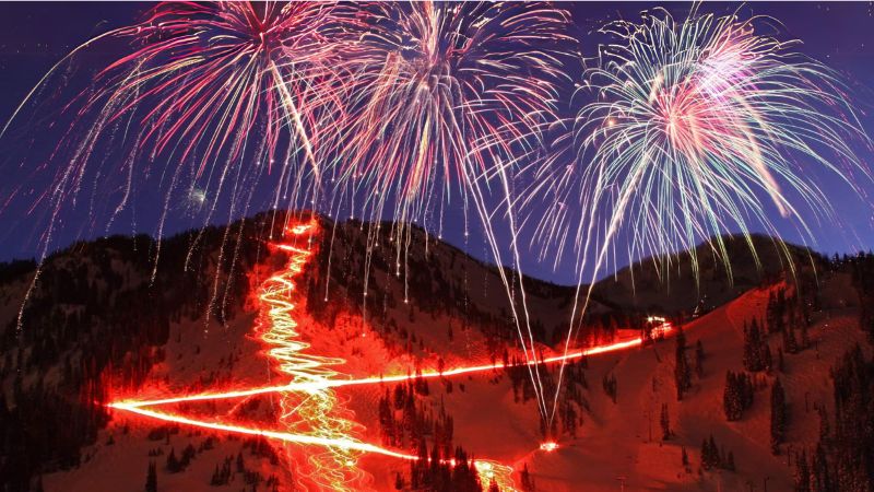 red lights coming down a mountain and fireworks in the sky for the 'Torchlight Parade' annual event in Bear Lake