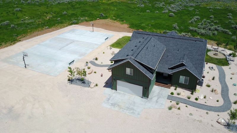 An aerial view of a single-story, suburban home with a dark gray roof and green siding. 